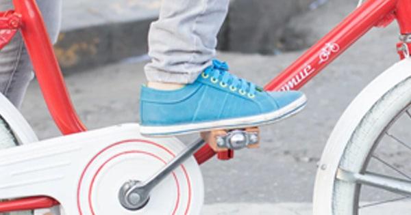 red bicycle with a foot wearing a blue shoe resting on pedal